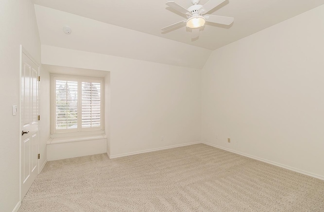 empty room featuring ceiling fan, baseboards, vaulted ceiling, and light colored carpet