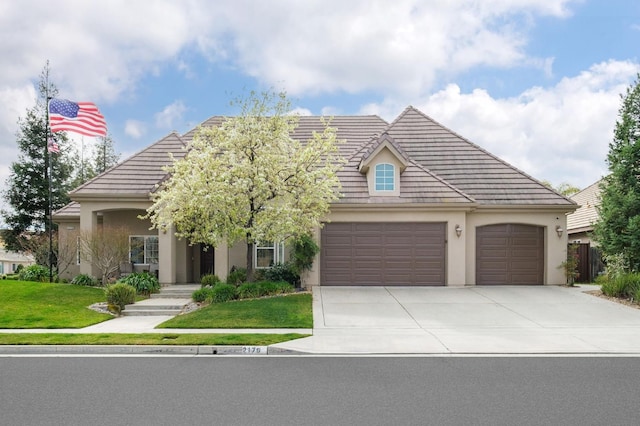 view of front of home with an attached garage, driveway, a front lawn, and stucco siding