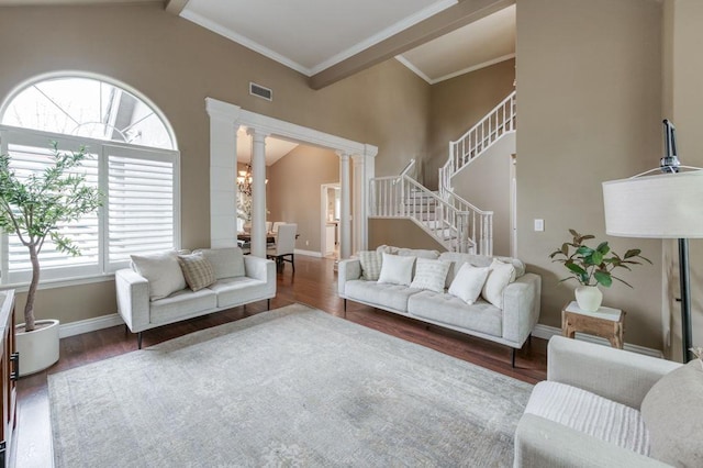 living area with dark wood-style floors, visible vents, and ornate columns