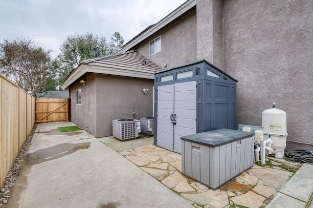 back of property featuring central AC unit, a patio, a gate, fence, and stucco siding