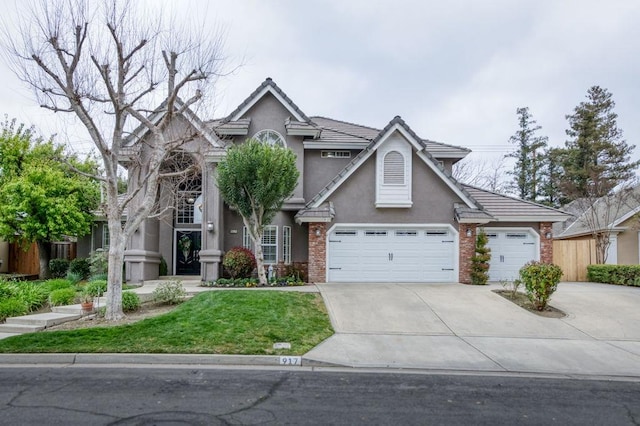 traditional home with brick siding, concrete driveway, an attached garage, a front yard, and stucco siding