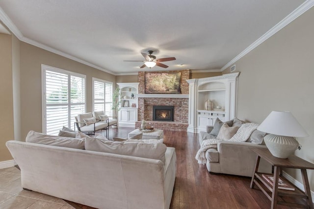 living room featuring ceiling fan, a fireplace, wood finished floors, visible vents, and ornamental molding