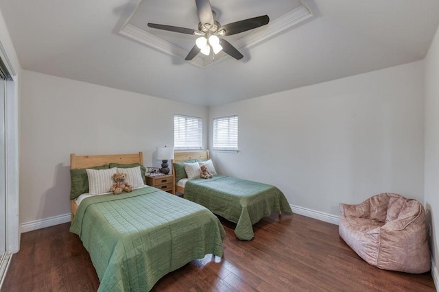 bedroom featuring a ceiling fan, a tray ceiling, dark wood-style flooring, and baseboards