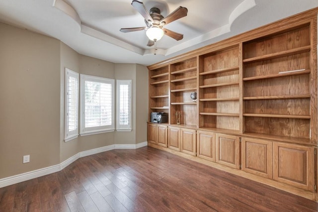 unfurnished room with dark wood-style floors, baseboards, a tray ceiling, and ceiling fan