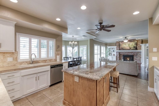 kitchen with a sink, a kitchen island, white cabinets, open floor plan, and stainless steel dishwasher