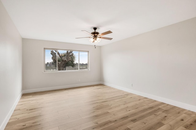 empty room with baseboards, a ceiling fan, and light wood-style floors