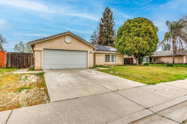 single story home with an attached garage, fence, driveway, roof mounted solar panels, and a front yard