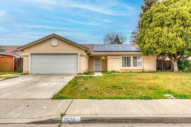 ranch-style house with a garage, solar panels, fence, stucco siding, and a front yard