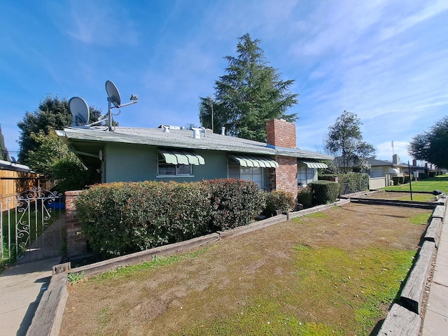 view of front of home featuring a chimney, a front yard, fence, and stucco siding