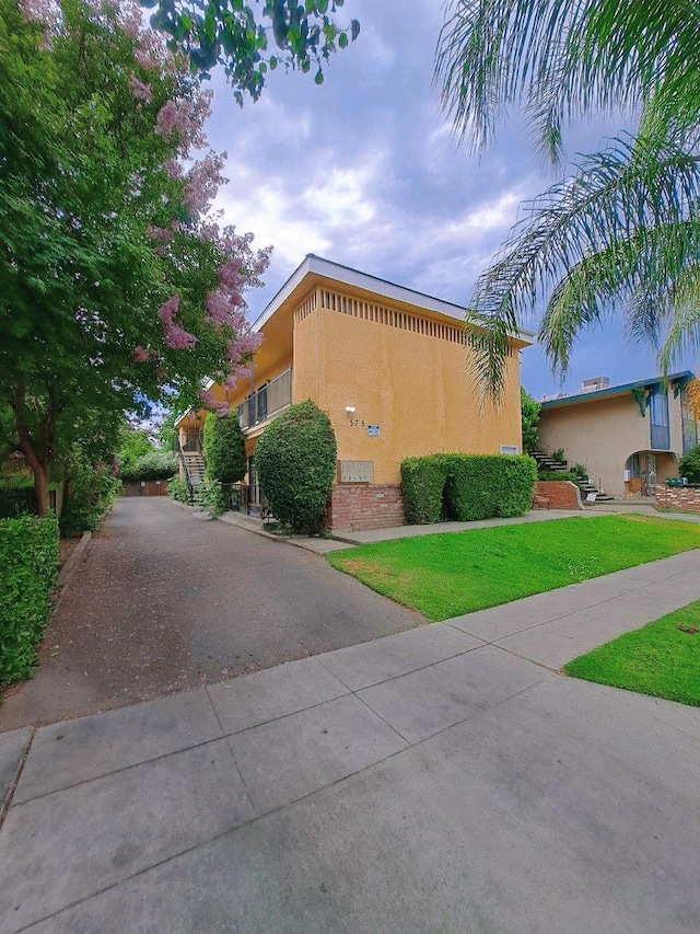 view of home's exterior with driveway, a lawn, and stucco siding