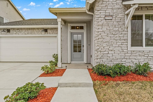 doorway to property featuring an attached garage, stone siding, concrete driveway, and stucco siding