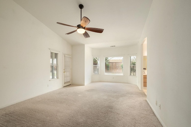 empty room with ceiling fan, vaulted ceiling, and light colored carpet