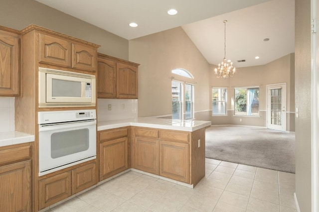 kitchen with a peninsula, white appliances, open floor plan, brown cabinets, and decorative light fixtures