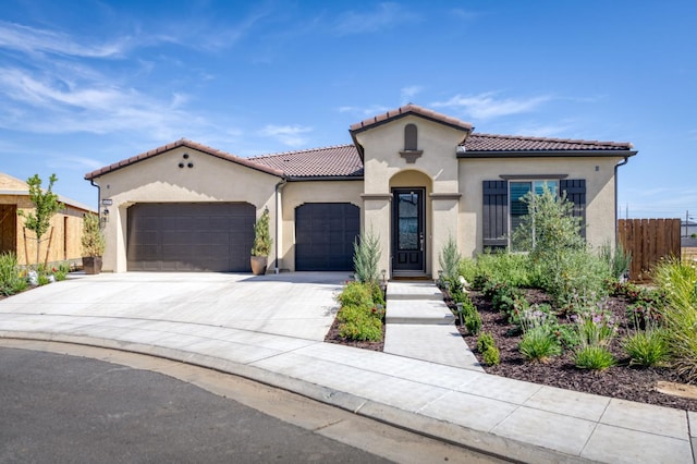 6375 E Millie Dr, Fresno, CA 93727 - mediterranean / spanish house featuring an attached garage, stucco siding, driveway, and a tiled roof