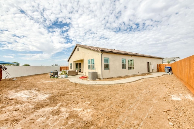 back of house with a fenced backyard, a patio area, outdoor lounge area, central AC, and stucco siding