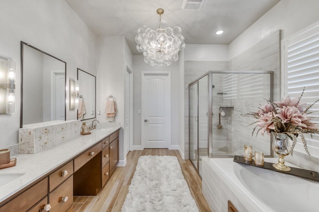 6375 E Millie Dr, Fresno, CA 93727 - bathroom with a stall shower, double vanity, a garden tub, wood finished floors, and a chandelier