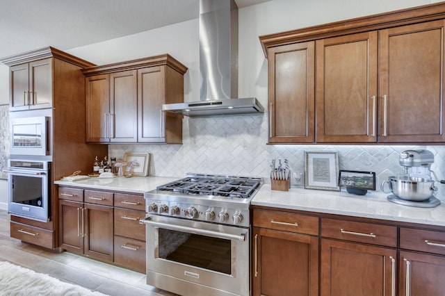 6375 E Millie Dr, Fresno, CA 93727 - kitchen featuring stainless steel appliances, wall chimney range hood, backsplash, light stone counters, and brown cabinets