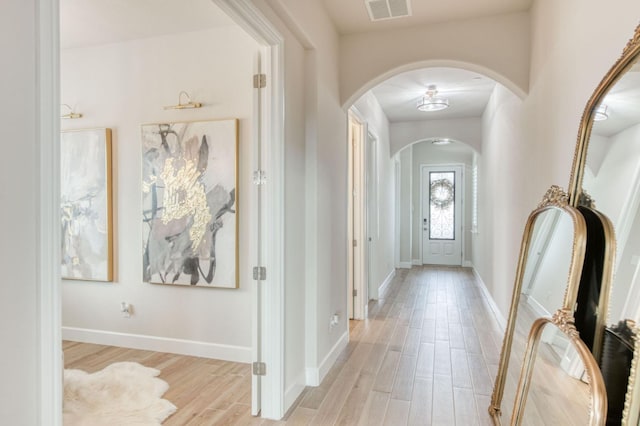 entryway featuring light wood-type flooring, baseboards, visible vents, and arched walkways