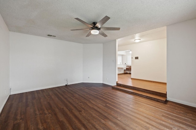 unfurnished room with dark wood-type flooring, visible vents, ceiling fan, and a textured ceiling