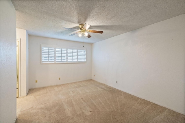 unfurnished room with a ceiling fan, light colored carpet, and a textured ceiling