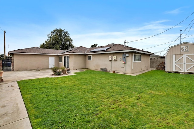 back of house featuring a patio, stucco siding, solar panels, a shed, and an outdoor structure