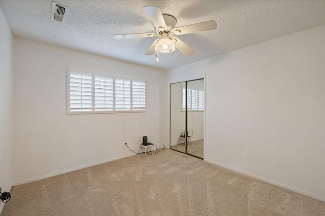 unfurnished bedroom featuring light carpet, a closet, a textured ceiling, and visible vents