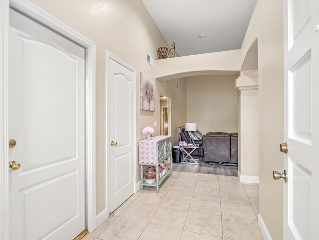 hallway with light tile patterned flooring, visible vents, and baseboards