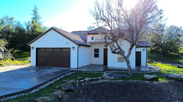 view of front of house featuring a garage, stucco siding, driveway, and a tiled roof