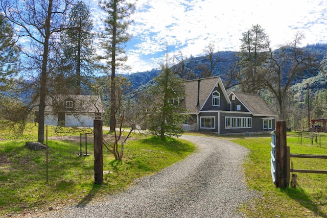 view of front of property featuring a front yard, gravel driveway, a mountain view, and fence