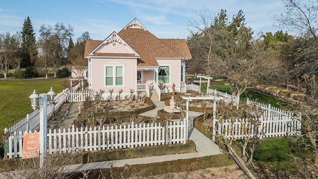 victorian-style house featuring a fenced front yard and roof with shingles