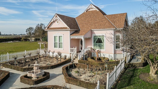 victorian home with a fenced front yard and a shingled roof