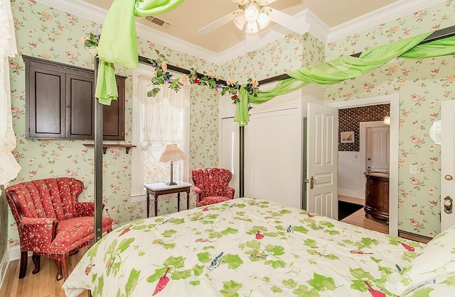 bedroom with crown molding, wood finished floors, visible vents, and wallpapered walls