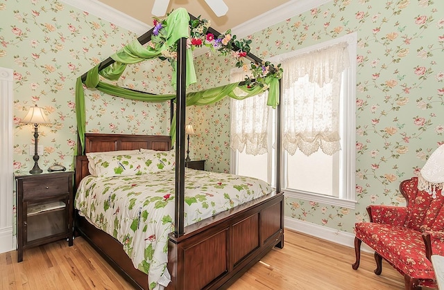 bedroom with wallpapered walls, light wood finished floors, baseboards, ceiling fan, and ornamental molding