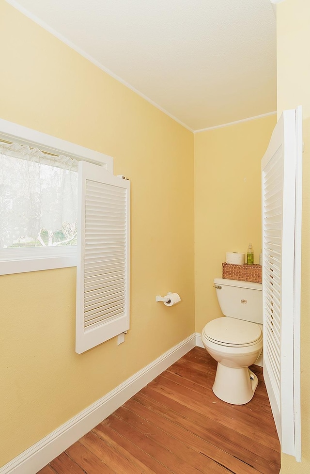 bathroom with baseboards, crown molding, toilet, and wood finished floors