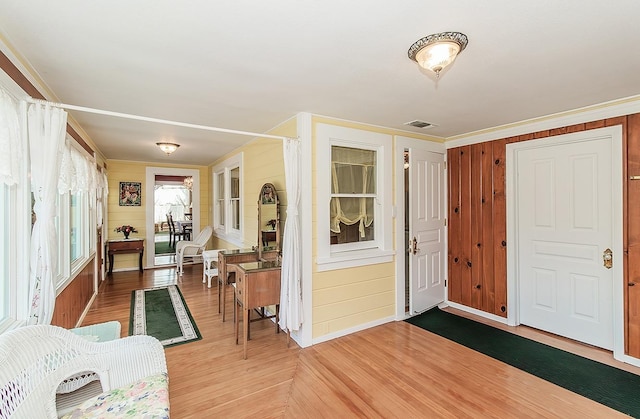 entryway featuring wooden walls, wood finished floors, and crown molding