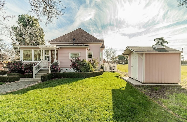 exterior space with a sunroom, fence, an outdoor structure, and a shed