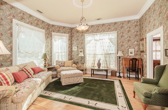 living room featuring a healthy amount of sunlight, wood finished floors, visible vents, and wallpapered walls