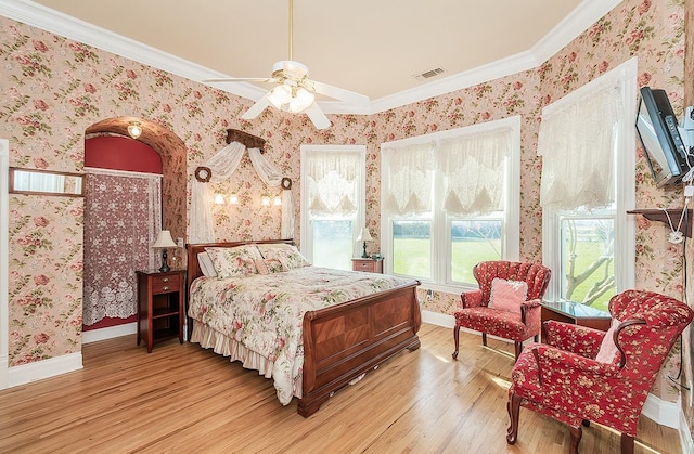 bedroom featuring wood finished floors, visible vents, baseboards, and wallpapered walls