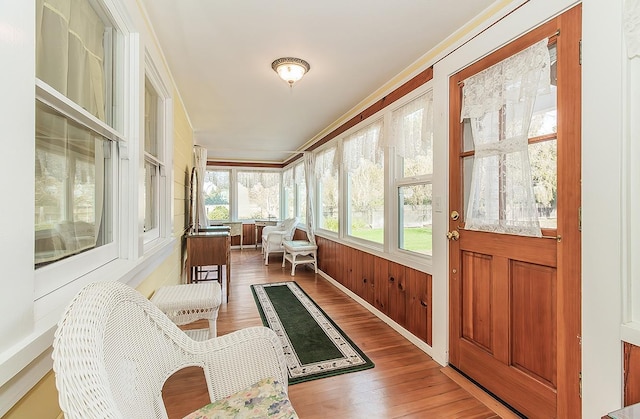 sunroom / solarium with ornamental molding and wood finished floors