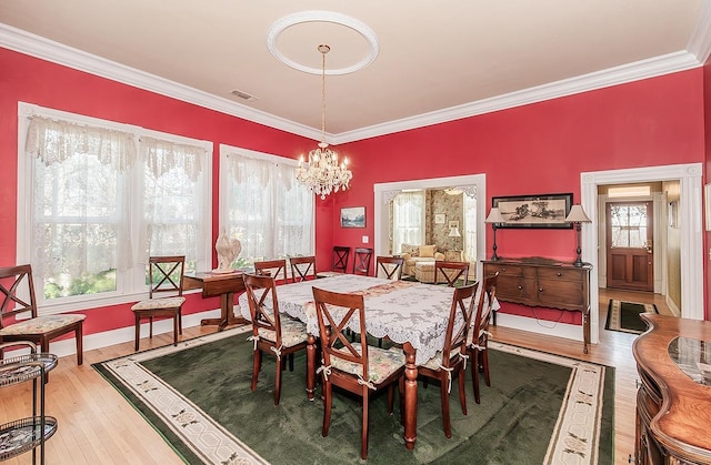 dining space with visible vents, baseboards, wood finished floors, crown molding, and a notable chandelier