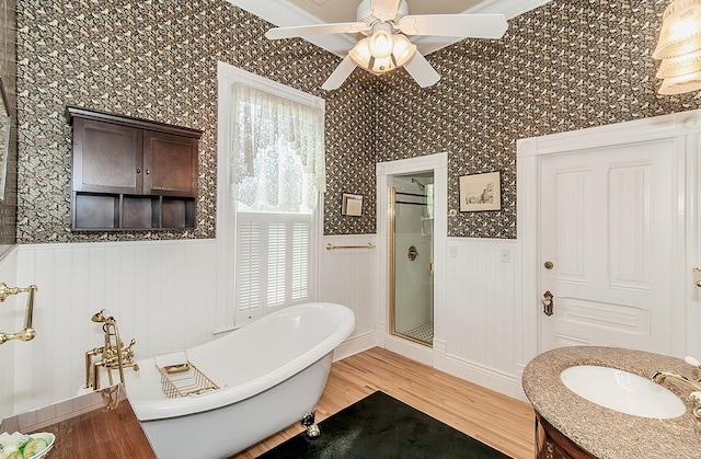 full bath with a wainscoted wall, a stall shower, a soaking tub, and wood finished floors