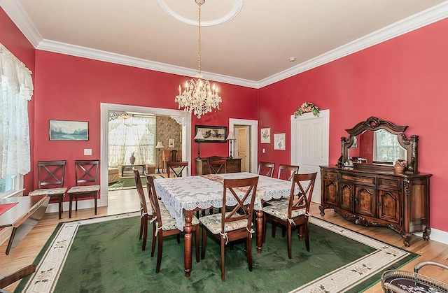 dining area featuring a chandelier, baseboards, wood finished floors, and crown molding