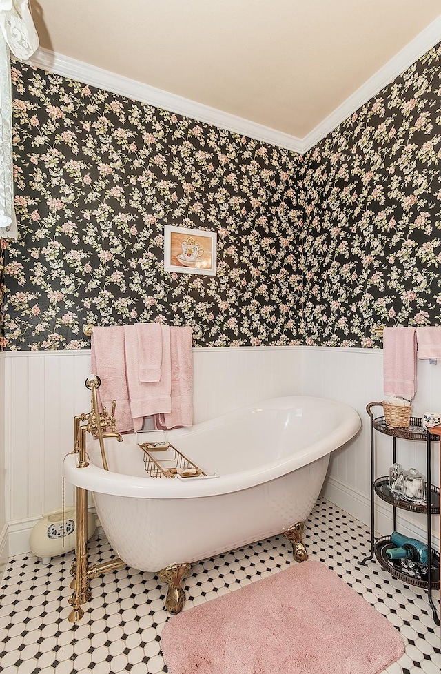 full bathroom with ornamental molding, a freestanding tub, wainscoting, and wallpapered walls