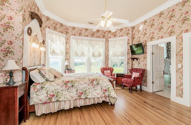 bedroom with ceiling fan, ornamental molding, wallpapered walls, and wood finished floors
