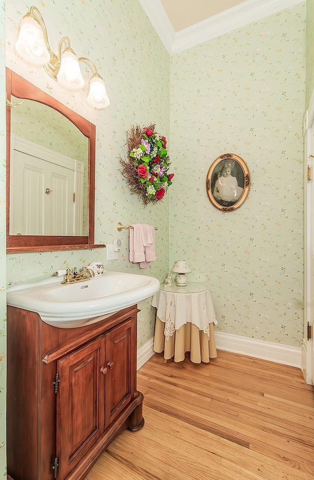 bathroom featuring ornamental molding, wood finished floors, and wallpapered walls