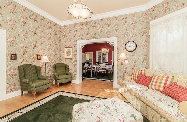 living area featuring ornamental molding, light wood-type flooring, a notable chandelier, and wallpapered walls