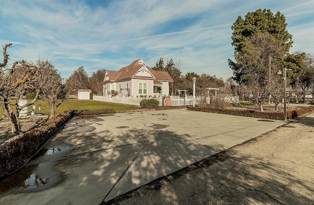 view of front of house featuring driveway, fence, and basketball court