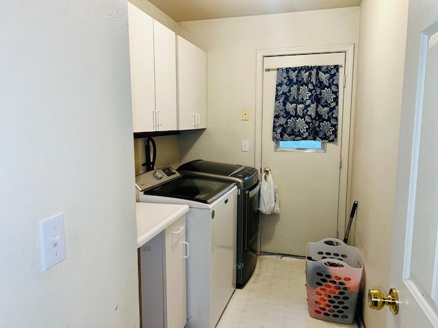 clothes washing area with cabinet space, washing machine and clothes dryer, and light floors