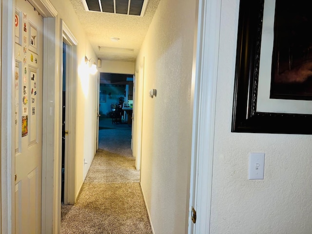 hall with light carpet, visible vents, a textured ceiling, and a textured wall