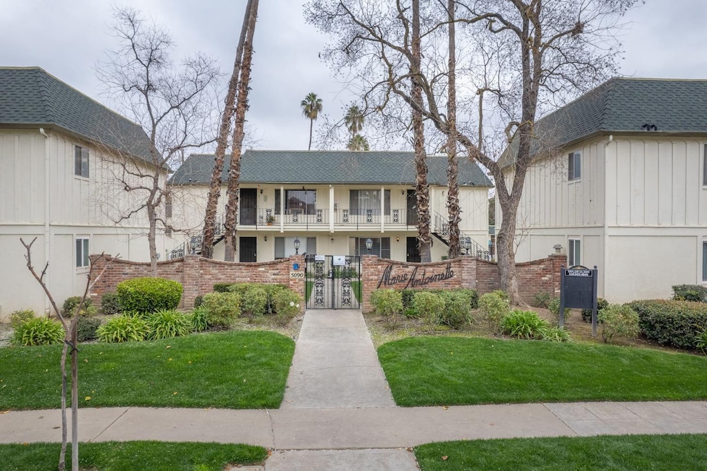 5090 N Roosevelt Ave Unit 6, Fresno, CA 93704 - view of front of house with a fenced front yard, brick siding, roof with shingles, a gate, and a balcony